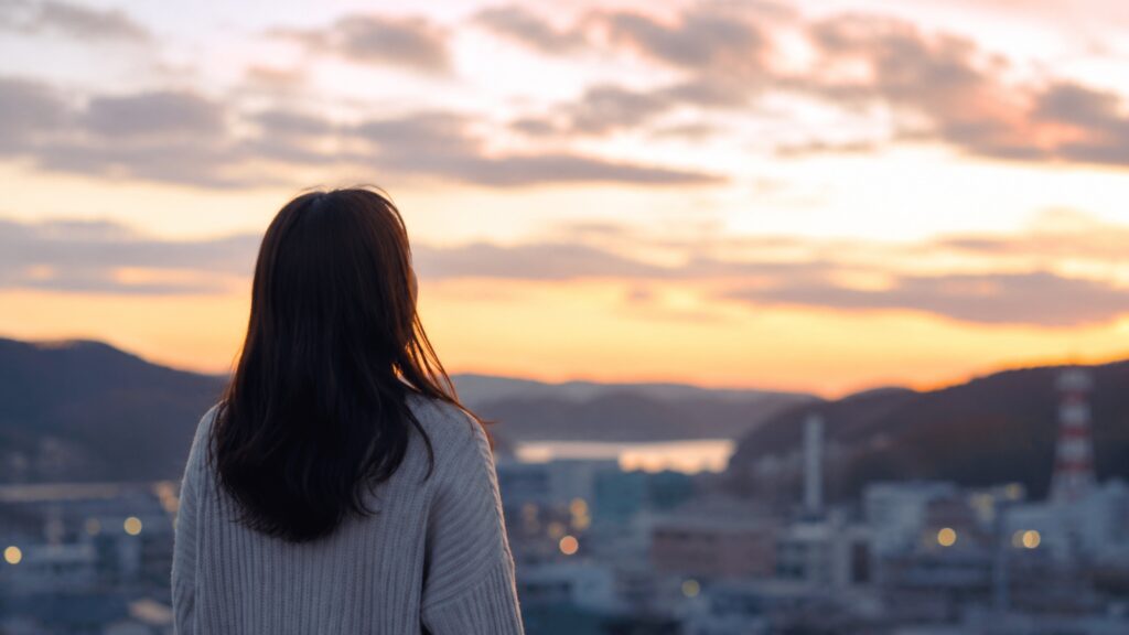 夕暮れの釜石の街を見つめながら未来を思い描く女性の後ろ姿